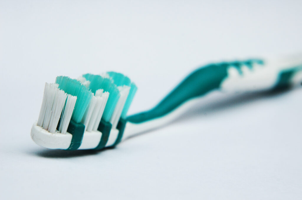 A close-up view of a toothbrush featuring green and white bristles, highlighting its design and color contrast.